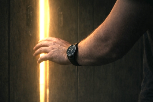 A hand reaching toward a door, light coming through the crack